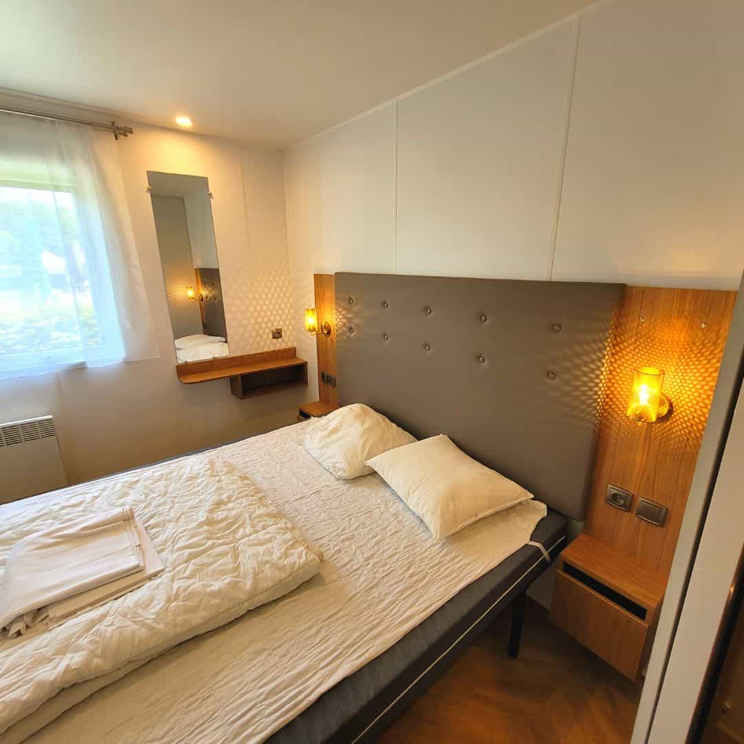 Grote slaapkamer met tweepersoonsbed in stacaravans op de camping in de Ardennen